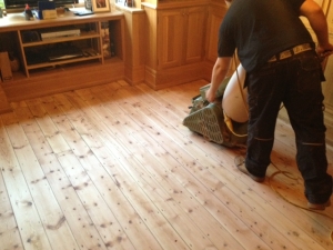 Using the sanding machine to sand floorboards